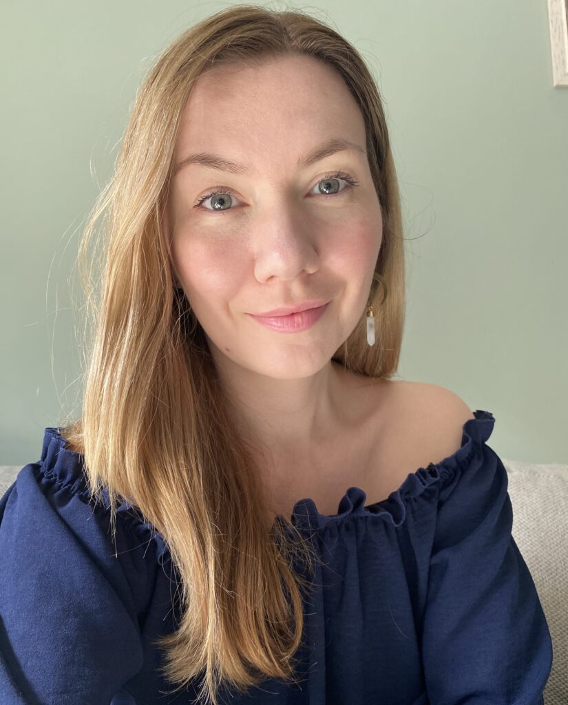 Psychologin lächelt vor neutralem Hintergrund in die Kamera.